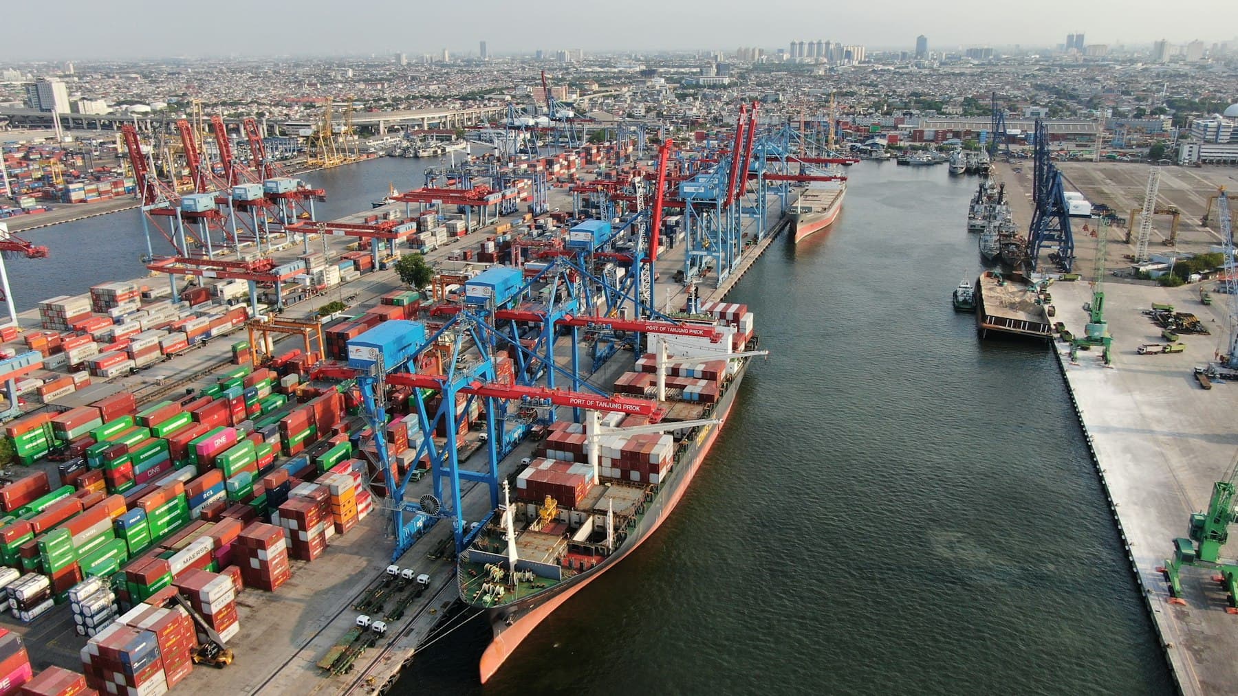 Container ship being loaded by cranes at a busy shipping port