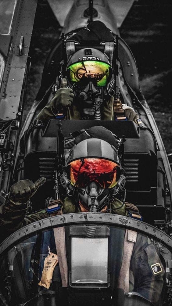 Two pilots in the cockpit of a fighter aircraft, each signalling ready