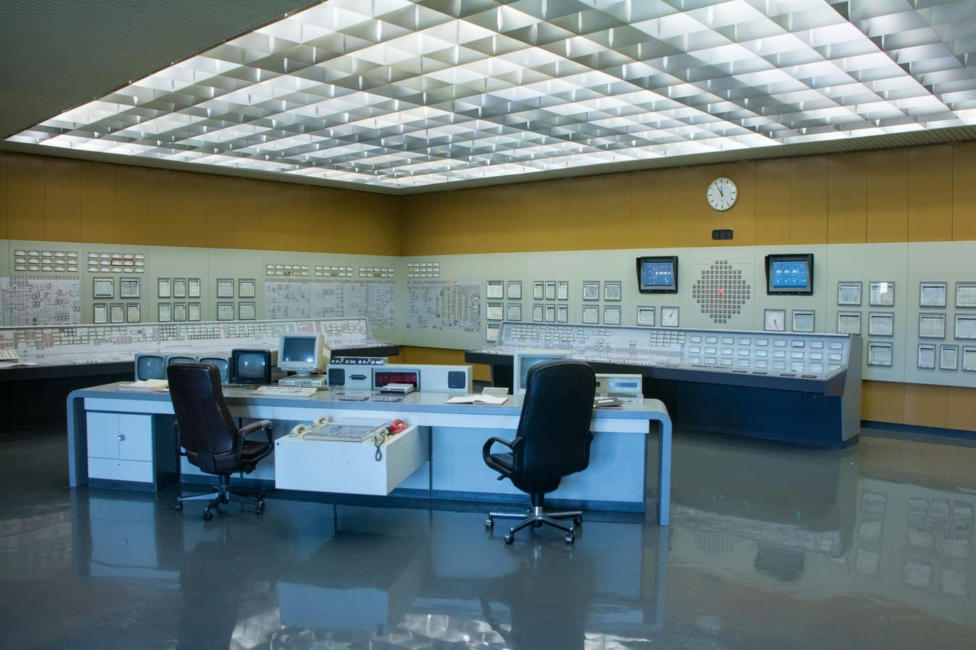 Power station control room with a wall mounted mimic panel and legacy operator consoles