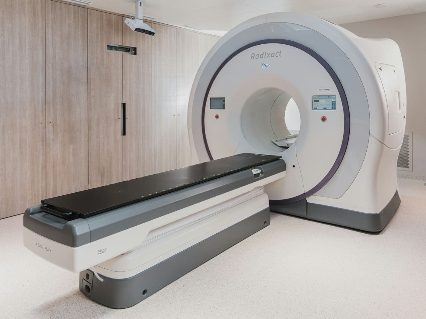A computed tomography scanner with its gantry and patient couch standing in an empty imaging room