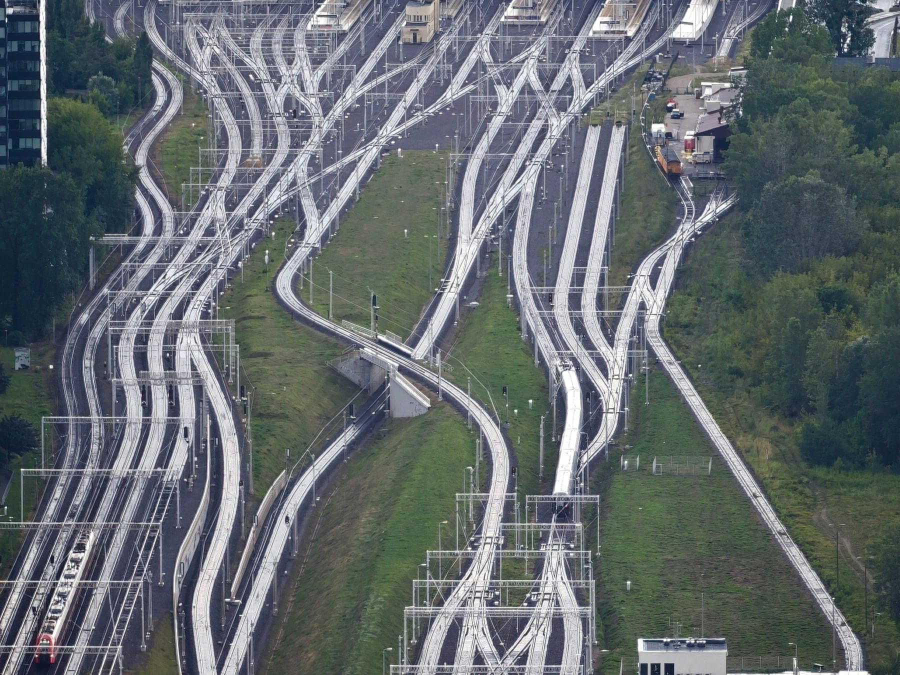 A multi track railway approach with signal gantries and overhead line equipment running into a station