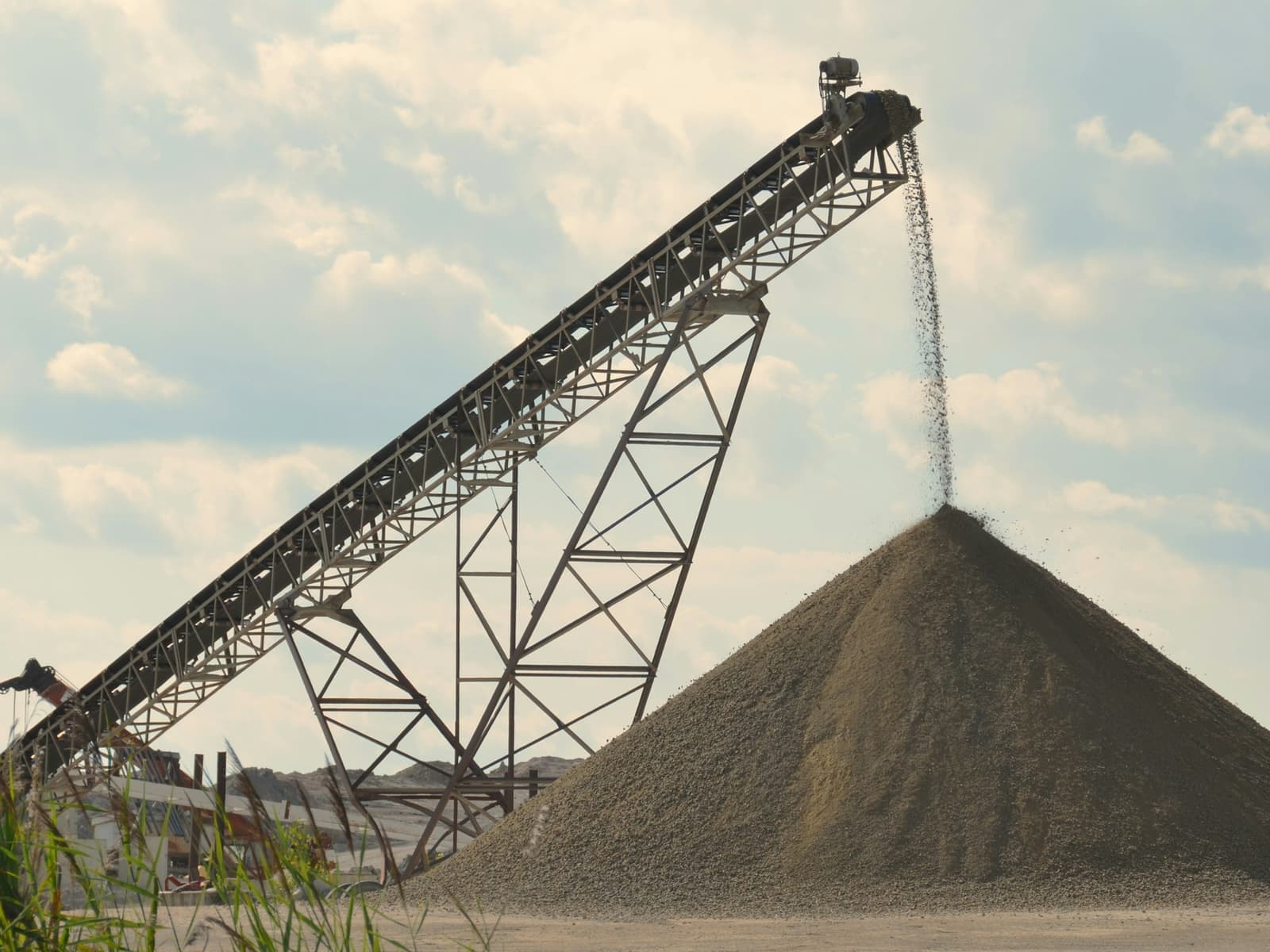 Radial stacker conveyor discharging crushed material onto a conical stockpile at a materials handling yard