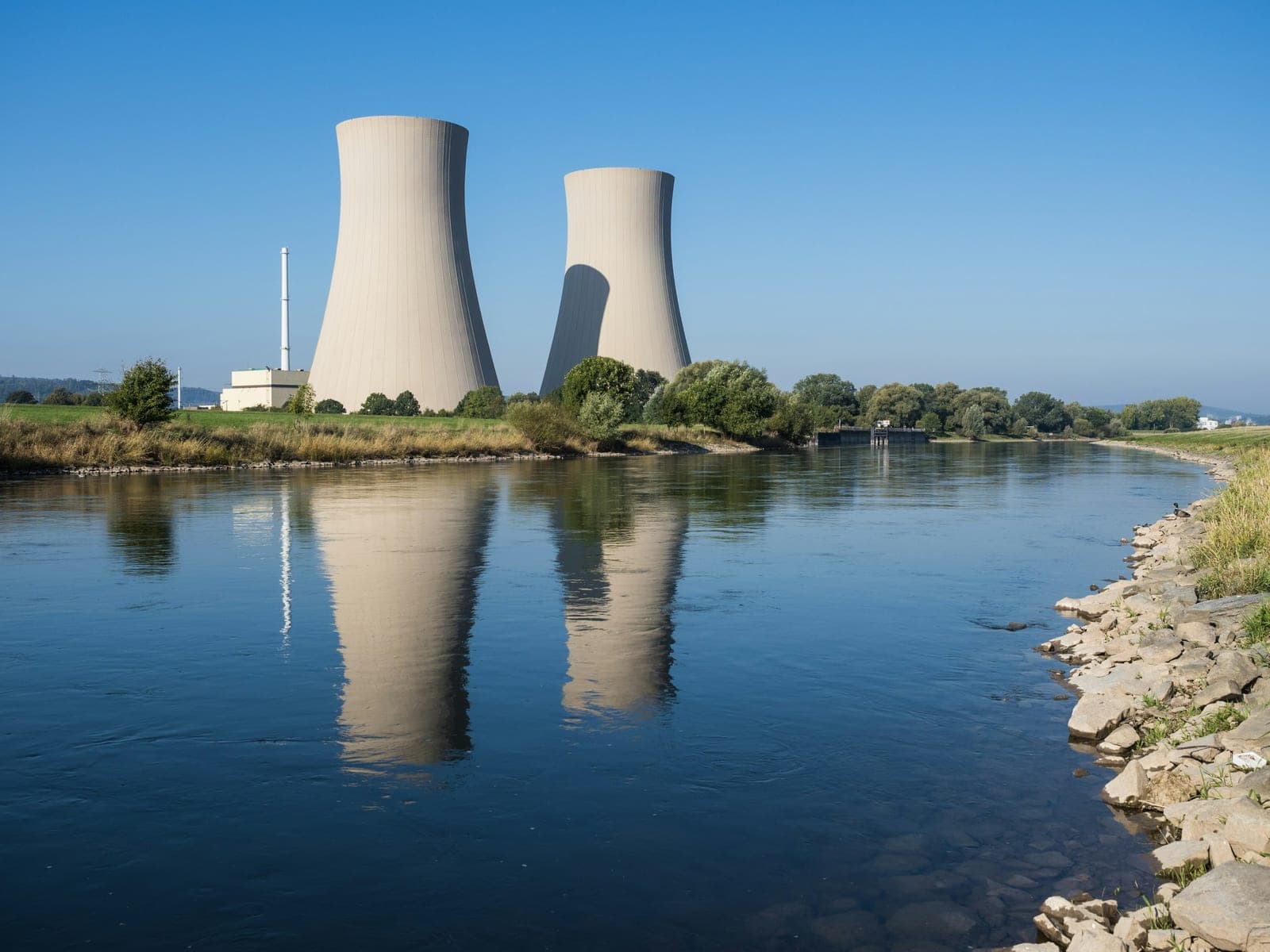 Operating nuclear power station with two cooling towers reflected in the river beside it