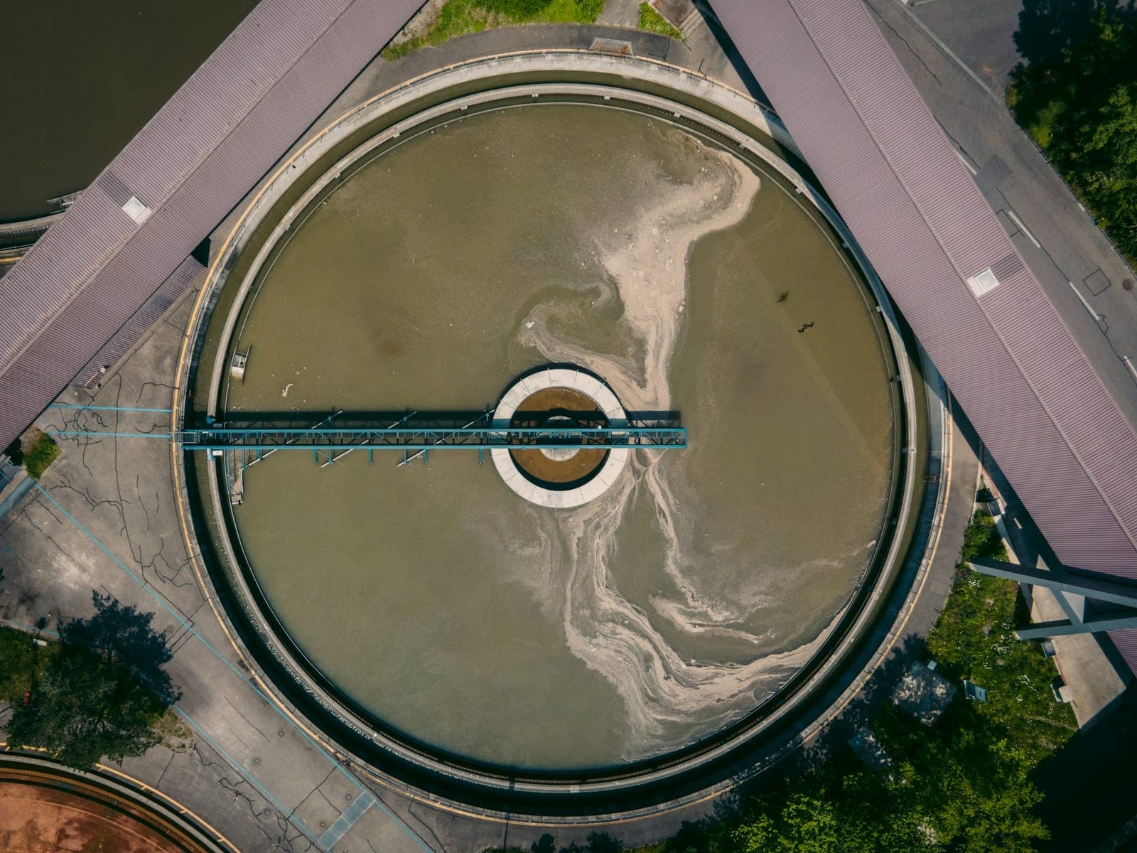 A circular clarifier photographed from directly above, its rotating bridge crossing the tank from rim to centre well