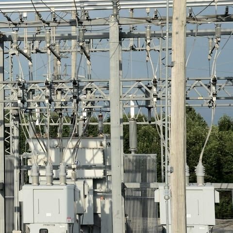 Distribution substation busbars, disconnect switches and a transformer behind its fence
