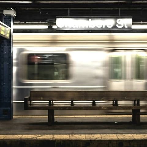 Train passing an underground station platform beside the platform seating